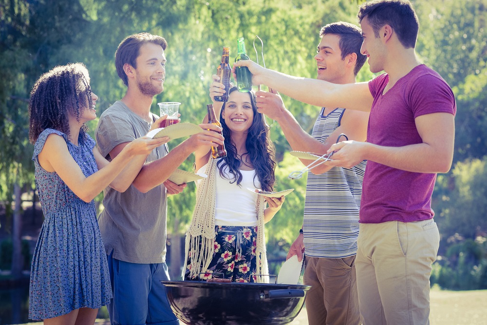 Happy friends in the park having barbecue on a sunny day